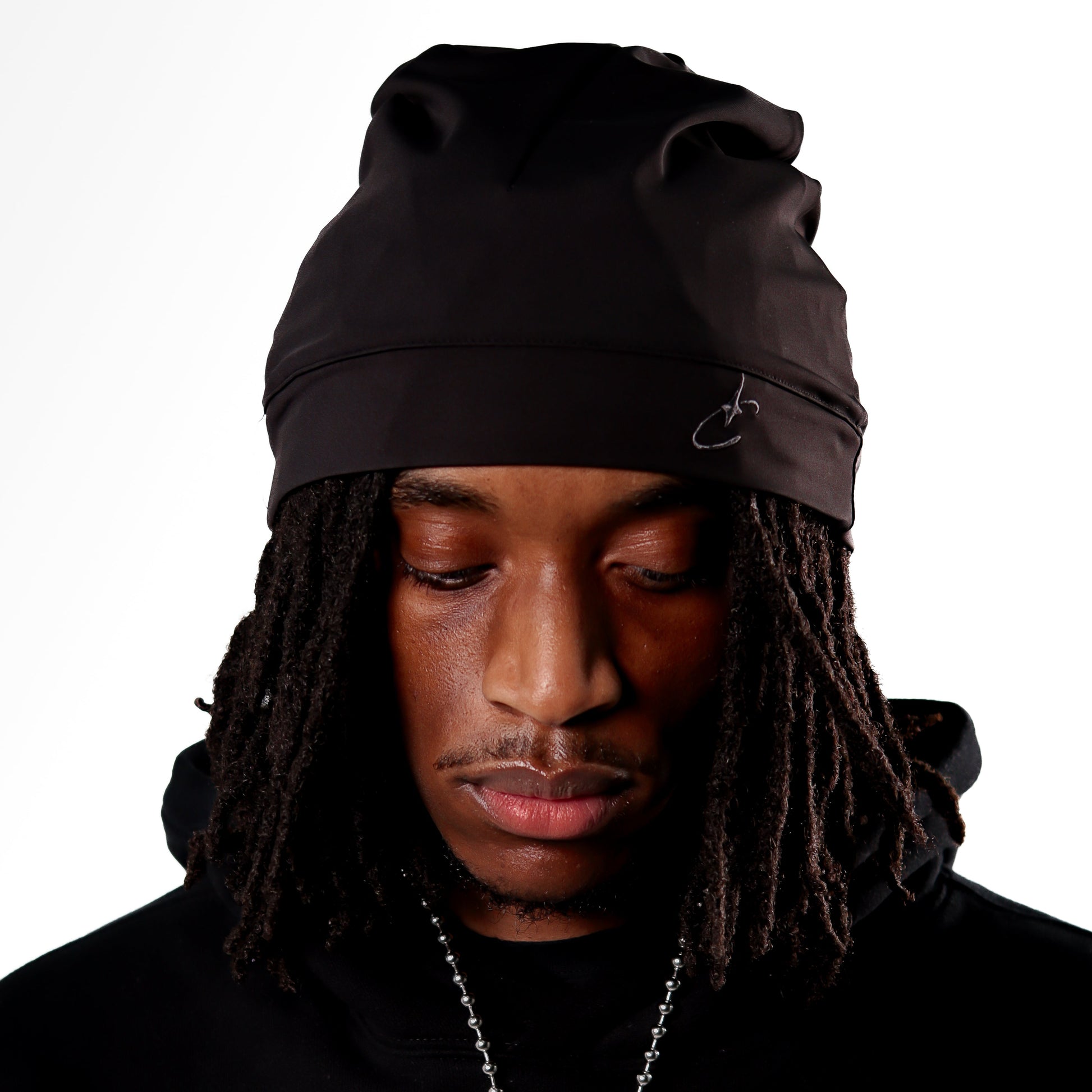 Person wearing a black beanie and hoodie on a white background